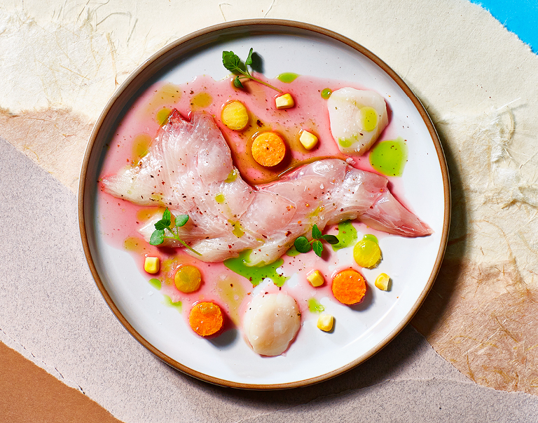 Tiradito is het Peruaanse antwoord op ceviche. De Dutch Yellowtail Kingfish wordt overgoten met een pittig mengsel van limoensap, rode peper, ui en koriander. De zachte smaak van zoete aardappel en mais zorgt voor evenwicht. Ook de coquilles worden licht gegaard in het pittige limoensapmengsel. Kori