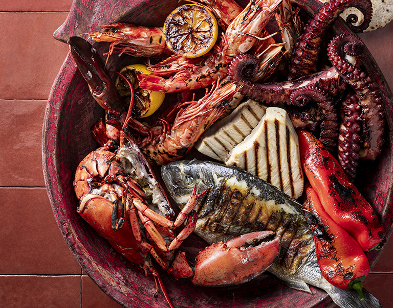 Een smakelijke barbecue-schotel met dorade, kreeft, octopus, garnalen en tonijn, geserveerd met geroosterde groenten en flatbread. 